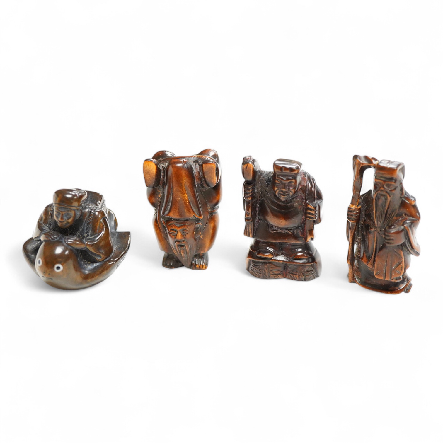 Four Japanese carved wood netsuke to include two elders and a novelty figure seated on a bird, largest 5cm high